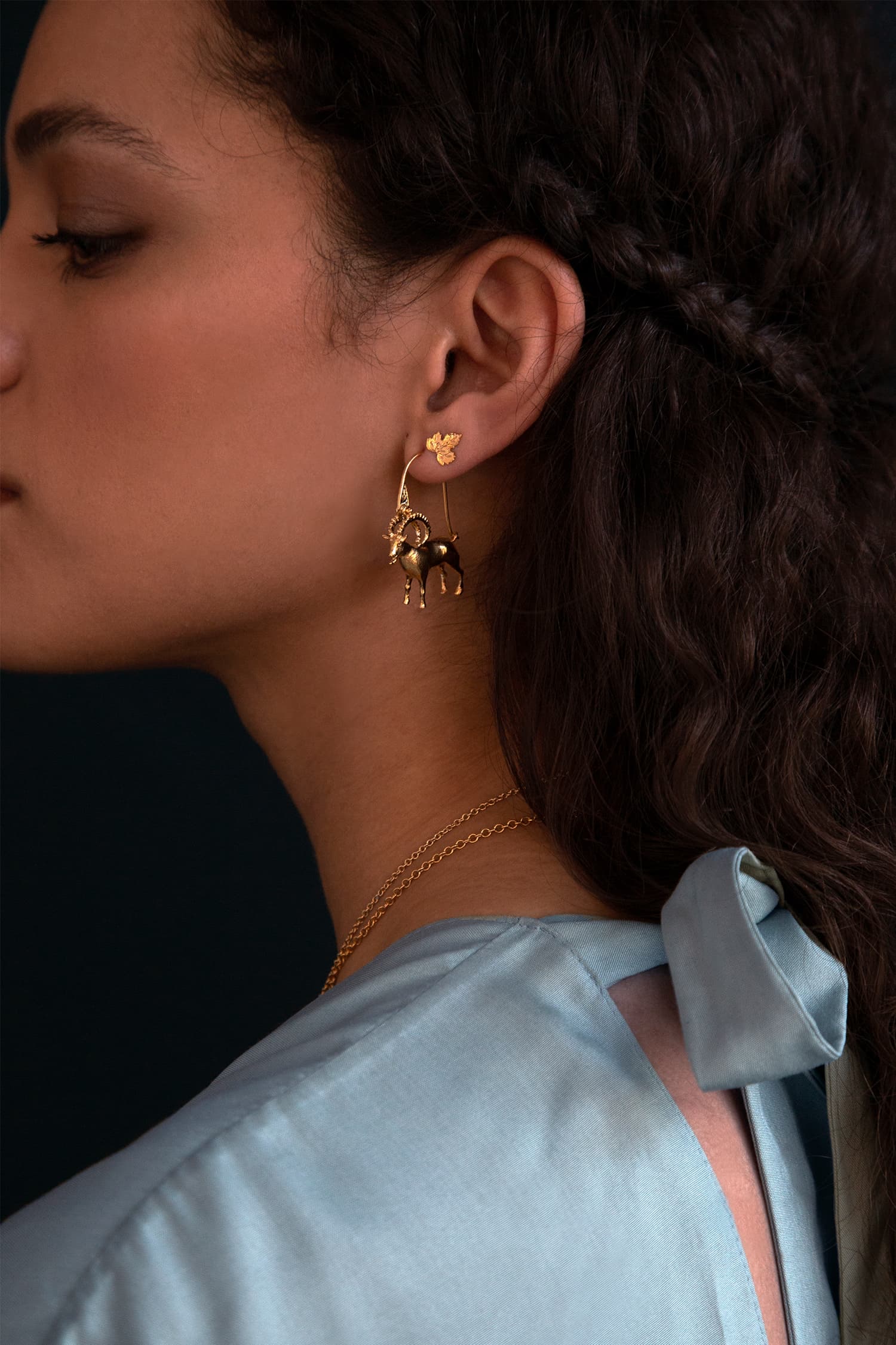 Model wears Fables Mountain Goat Creole Earrings in silver and gold plate