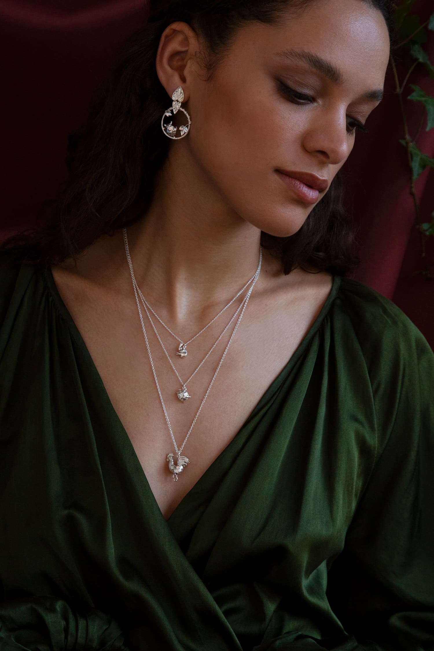 Model wears Fables silver necklaces and earrings featuring Hare and Tortoise, and a large rooster.