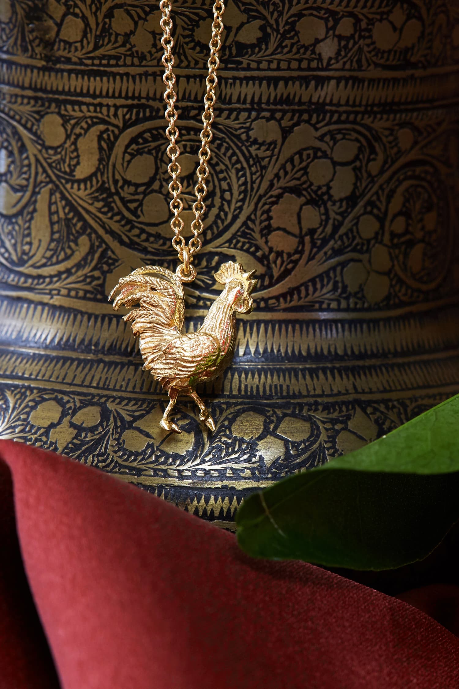 Gold plated Rooster necklace with organte illustrated background and green leaf