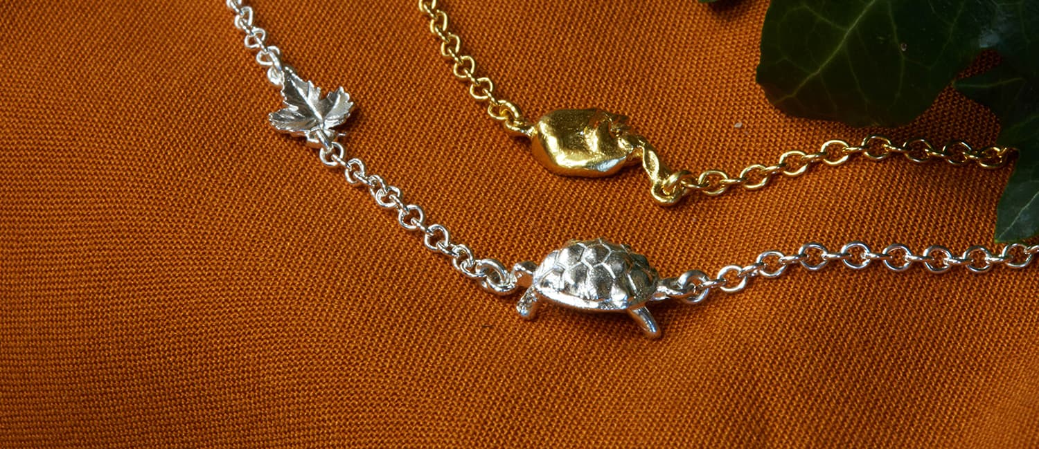 Hare and tortoise inline fairmined gold plated bracelets on rich orange fabric