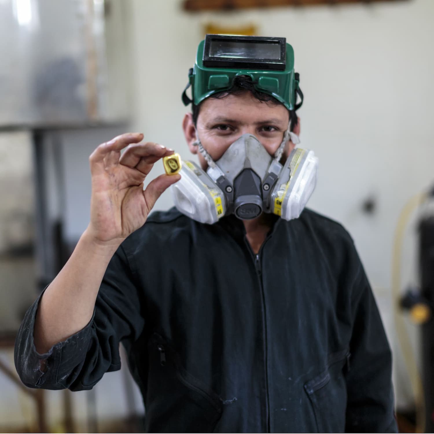 fairmined miner wearing breathing mask in workshop holding a piece of fairmined gold nugget