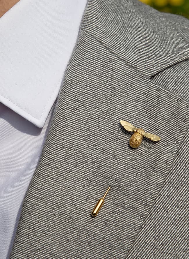 gold plated bee lapel pin worn by model on grey suit jacket