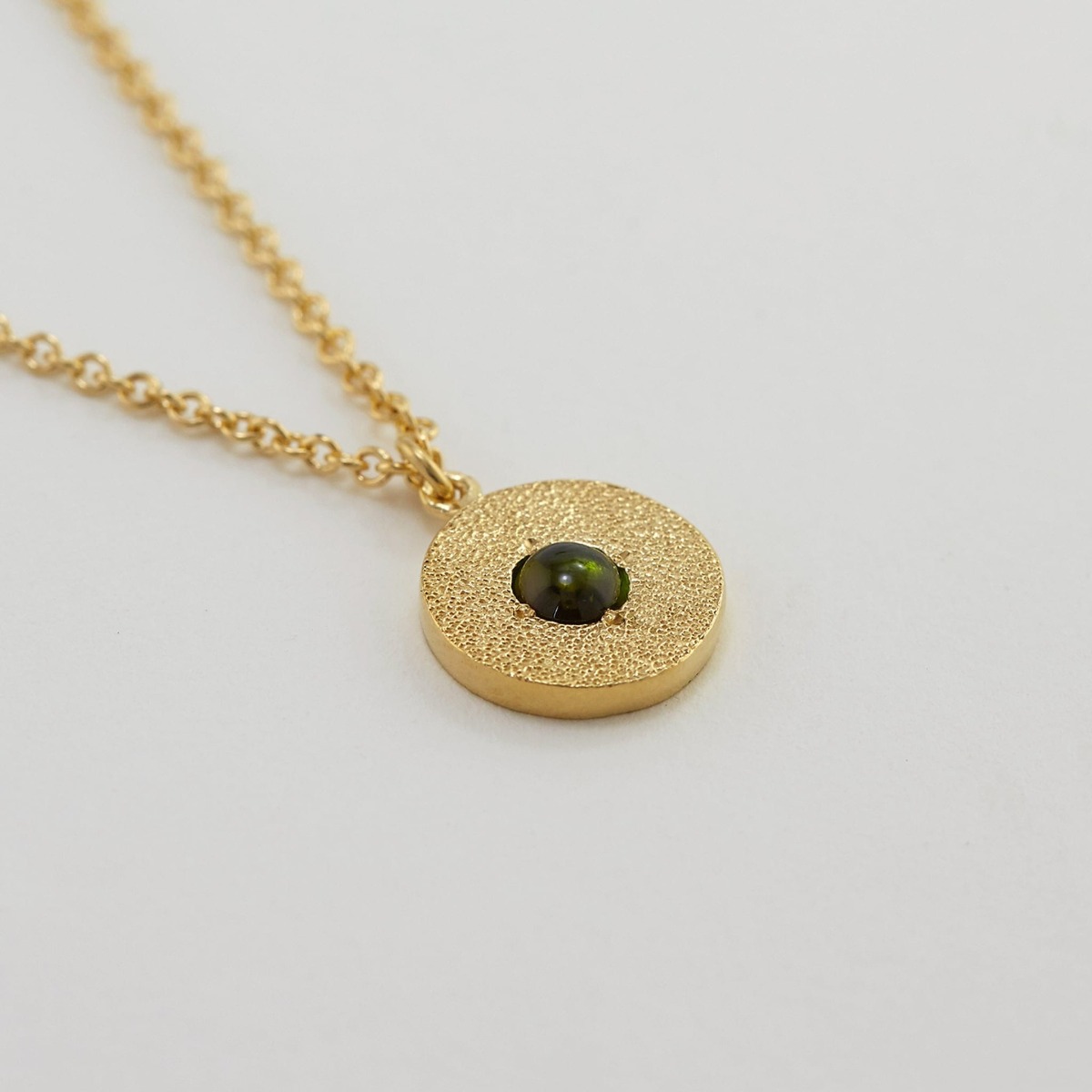 Paper shot of Iris Reversible Disc Green Tourmaline Necklace by Alex Monroe Jewellery