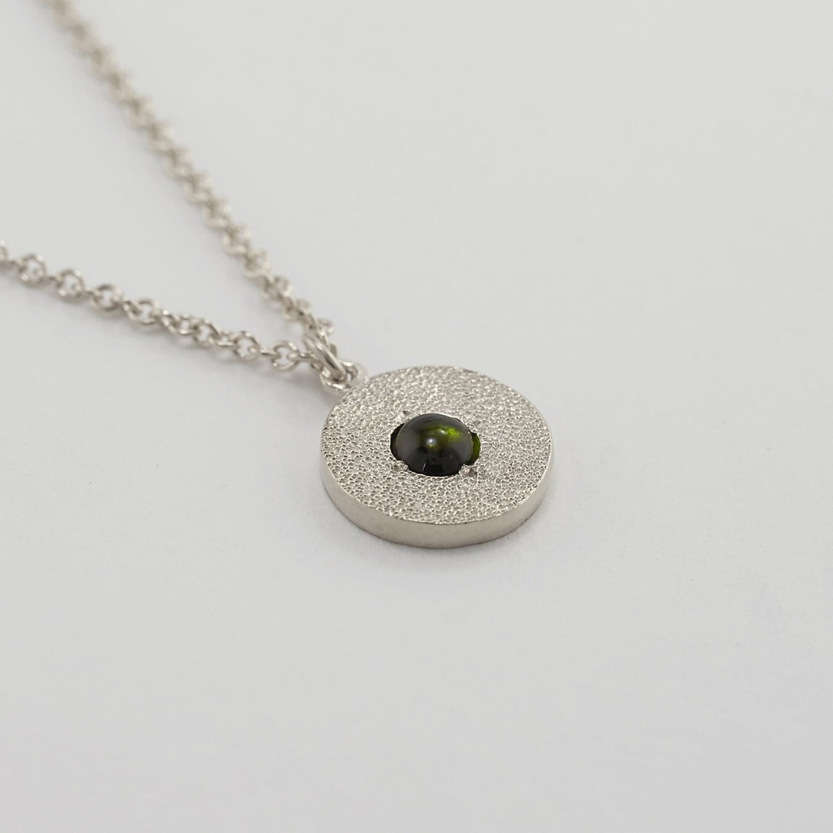 paper shot of Iris Reversible Disc Green Tourmaline Necklace by Alex Monroe Jewellery