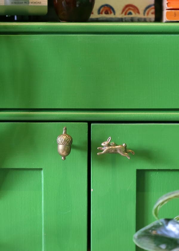 Acorn and leaping rabbit brass drawer handles on a vidid forest green painted cupboard.