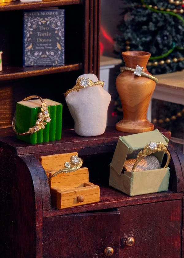 Selection of diamond engagement rings displayed in a tiny model shop. The engagement rings are textured, featuring flowers, vines, bees, and flowers.