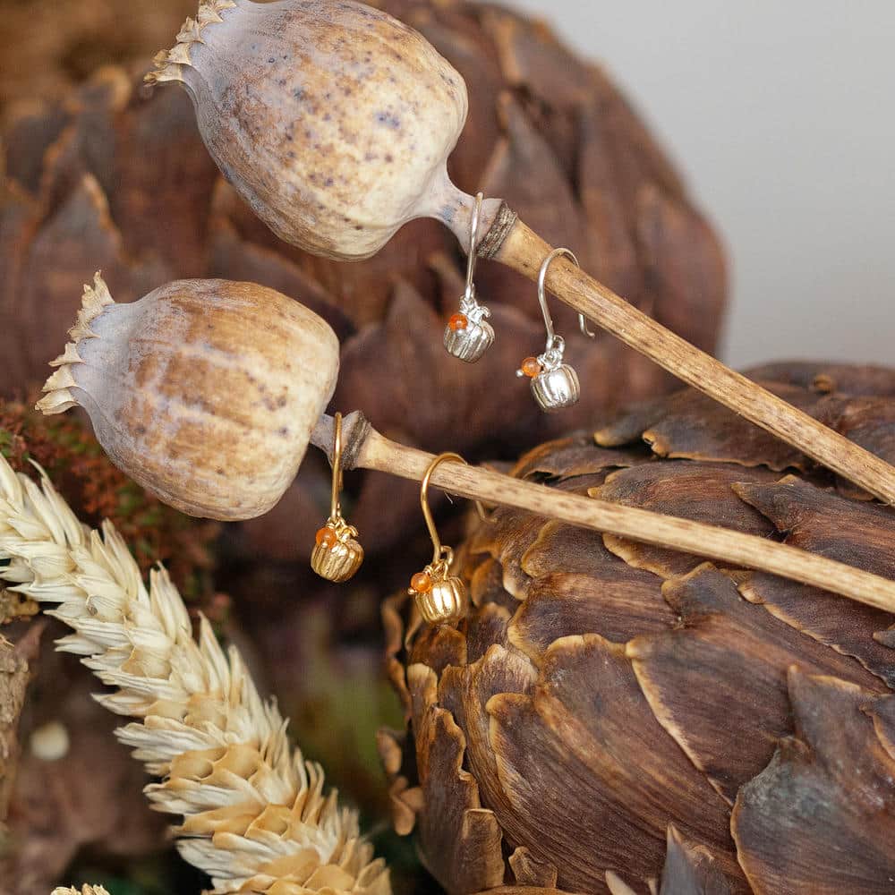 Gold and silver pumpkin necklaces with small gemstone charms, styled on a rustic artichoke background