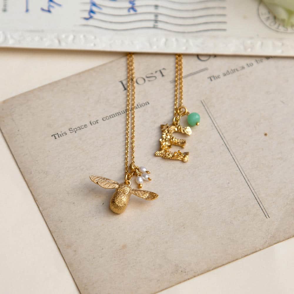 Gold baby bee necklace personalised with a set of 3 rice pearl charms and a Letter E floral Alphabet necklace with green chrysoprase gemstone.