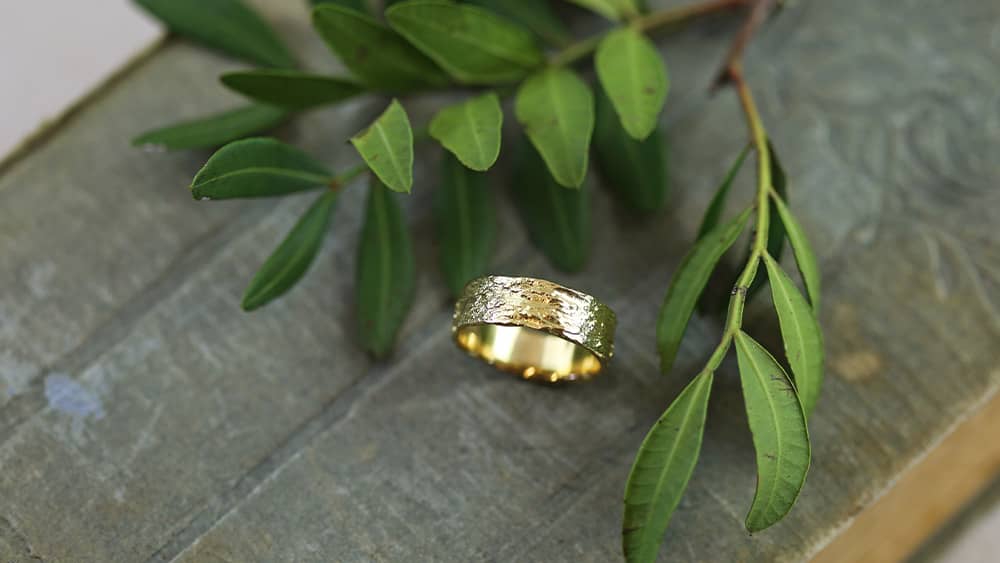 Three textured solid gold wedding bands, with diamonds.