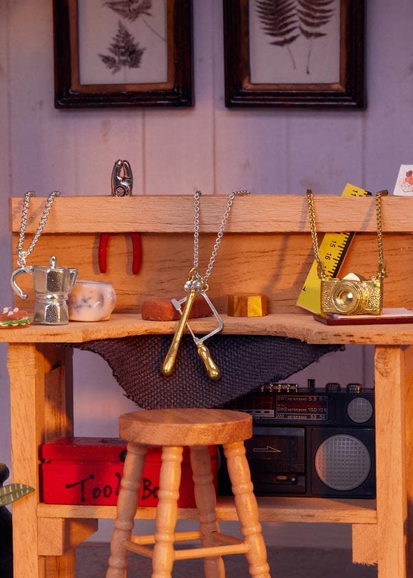 Moka coffee pot, jewellery tools and vintage camera necklaces on a tiny model jewellers workbench.