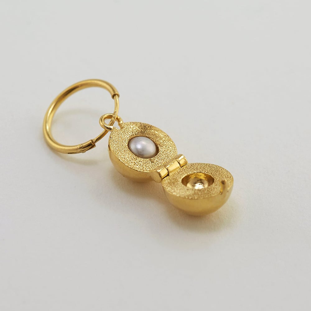 paper shot of gold plated Wears the Cannonball Single Opening Earring with Hidden Pearl by Alex Monroe Jewellery