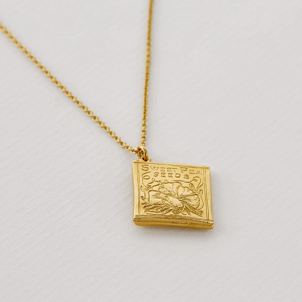 Paper shot of gold plated Sweetpea Seed Packet Necklace by Alex Monroe