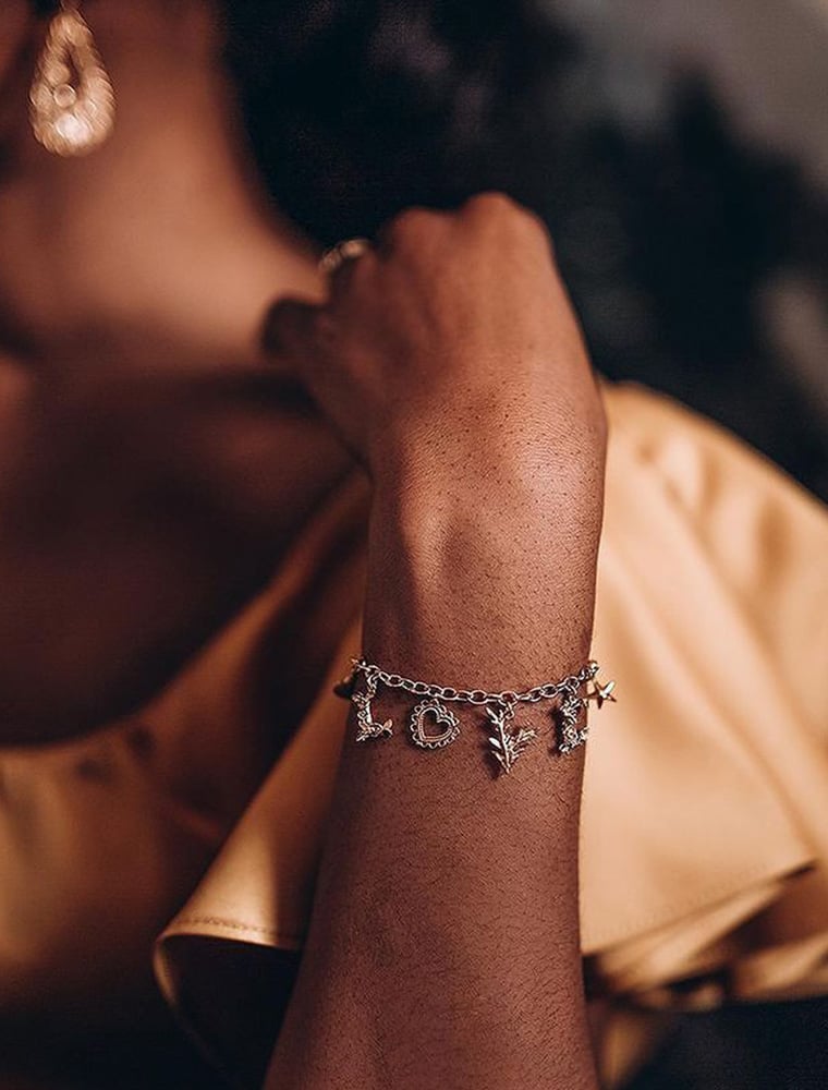 Onyi Moss wearing gold plated L O V E Mixed Charm Bracelet by Alex Monroe