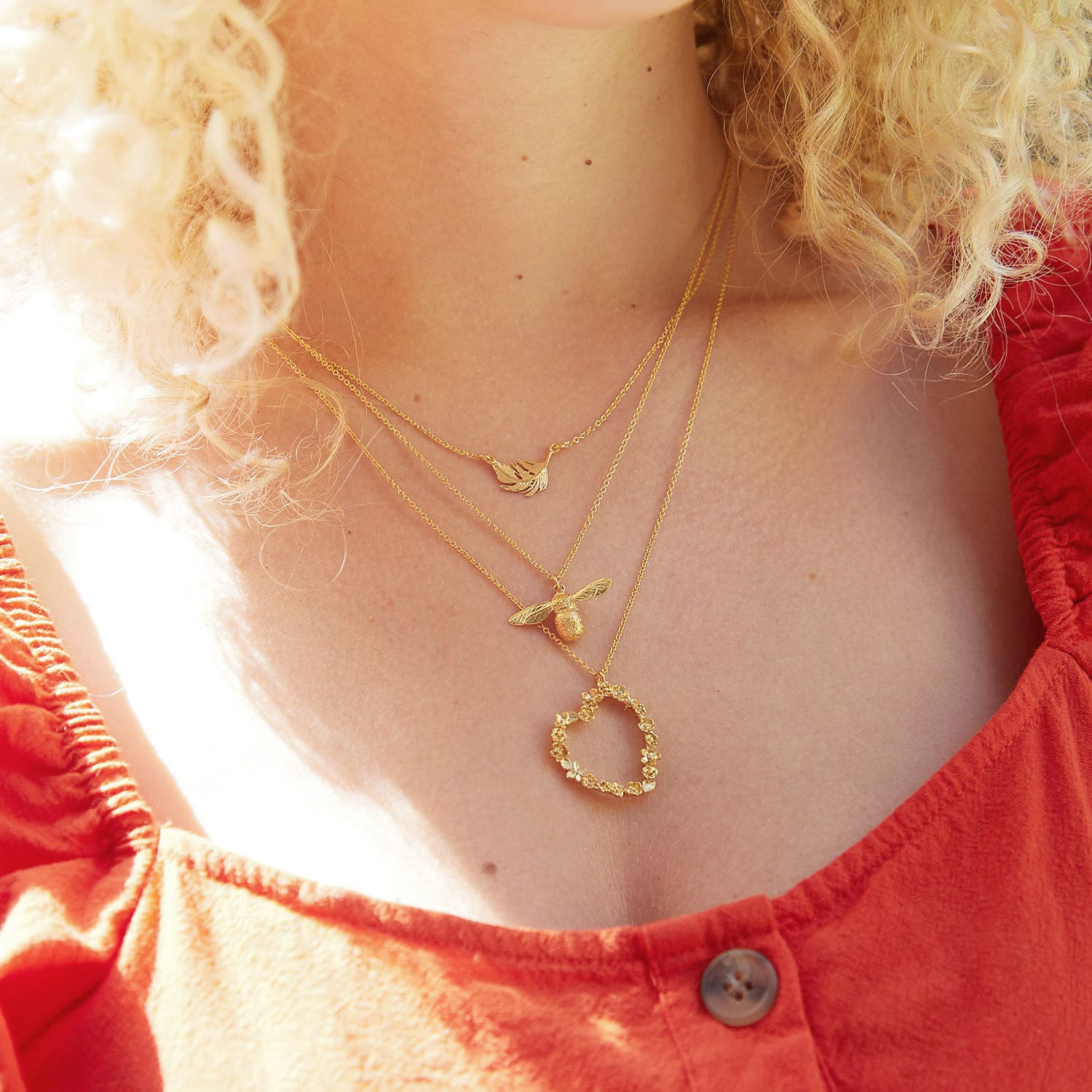 Layered silver and gold plate feather, baby bee and floral heart necklaces.
