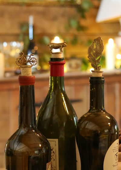 Wine Bottles displaying Crow Feather, Bianchi Bicycle, Suffolk Pig Brass & Cork Bottle Stopper