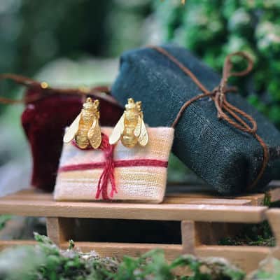 Gifts under £175 Honeybee gold plated stud earrings on a model sleigh with presents.