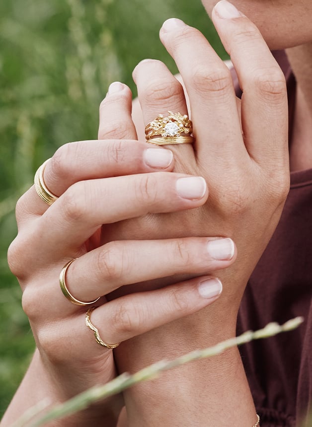 Close up of model wearing stacking rings and a Harvest Seed Ring with 0.7ct Central Diamond by Alex Monroe Fine Jewellery