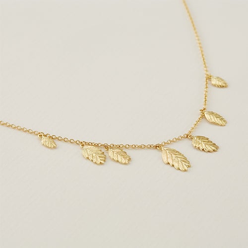 paper shot of a solid yellow gold Woodland Grass Necklace with Seven Seed Drops by Alex Monroe fine Jewellery