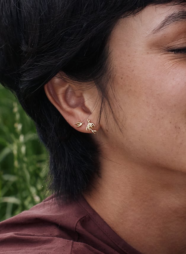 Close up of Model wearing Asymmetric Flyaway Oat Seed Stud Earrings from Alex Monroe's Golden Harvest Collection