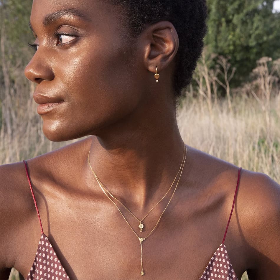 model wearing two layered alex monroe fine 18ct gold ammonite necklaces