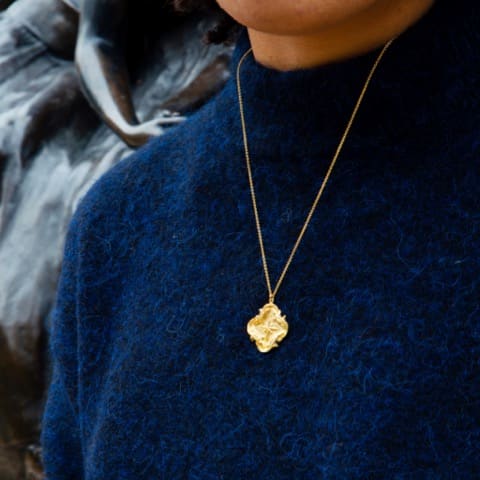 Model wears dark blue knit jumper and gold plated Guardian Compass Necklace
