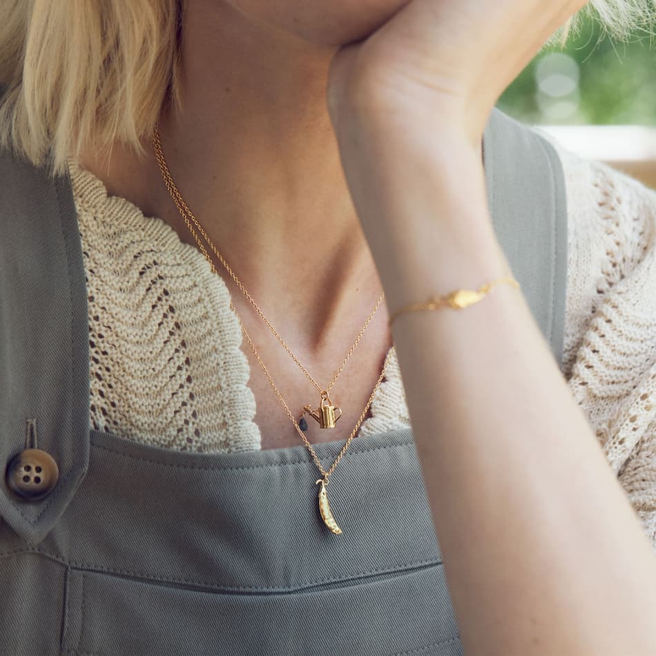 model wearing watering can and peapod necklace by alex monroe jewellery