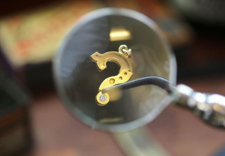 Using tweezers to hold an 18ct yellow gold ring casting on the forge whilst using a blow torch to heat the casting.