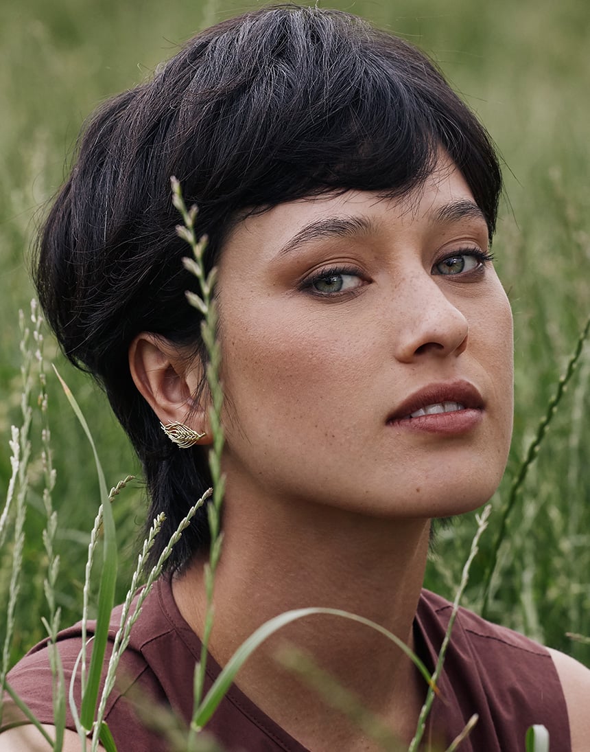 A shot of a model in a field wear Alex Monroe's Barley Two-Way Crawler Earrings from his new collection Golden Harvest