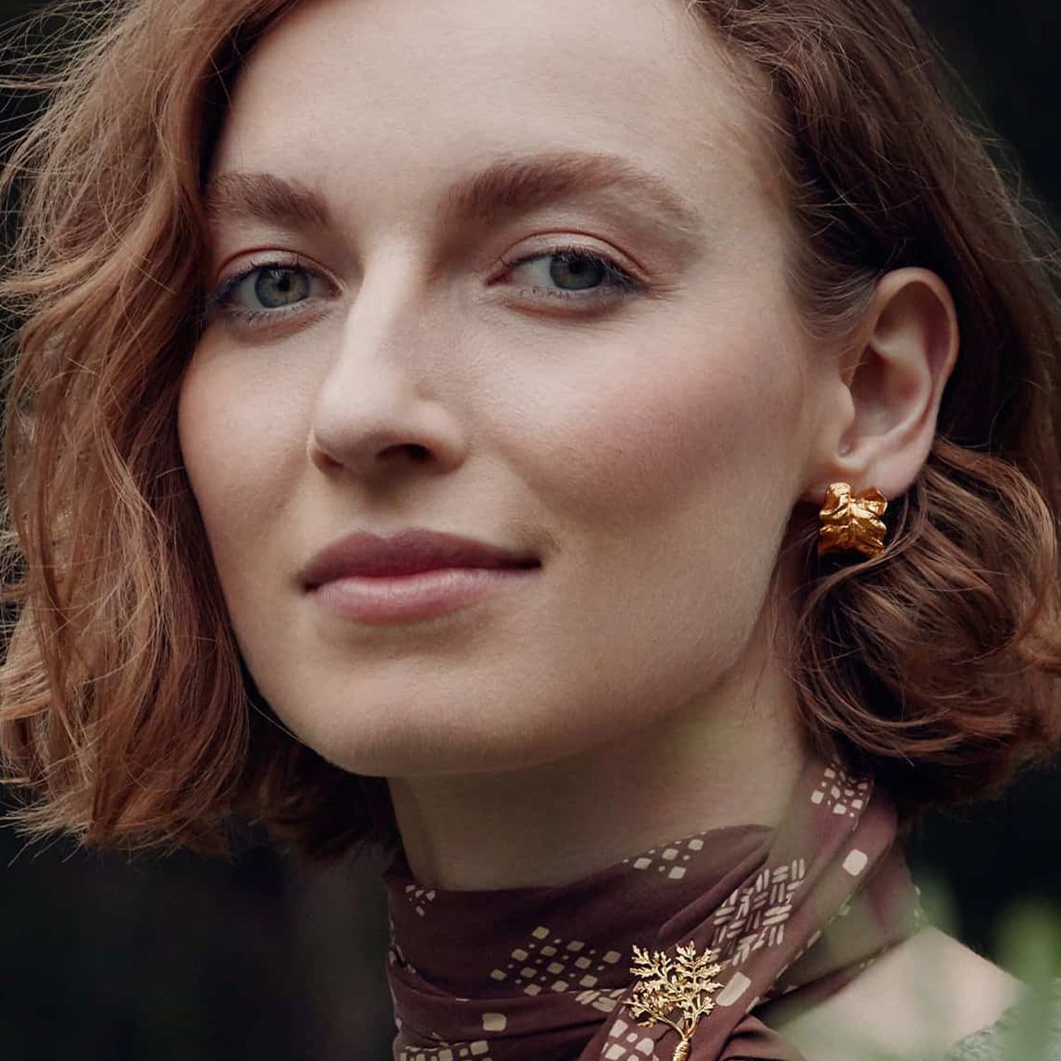 Model wearing gold plated Chard Leafy Hoop Earrings earring by Alex Monroe Jewellery
