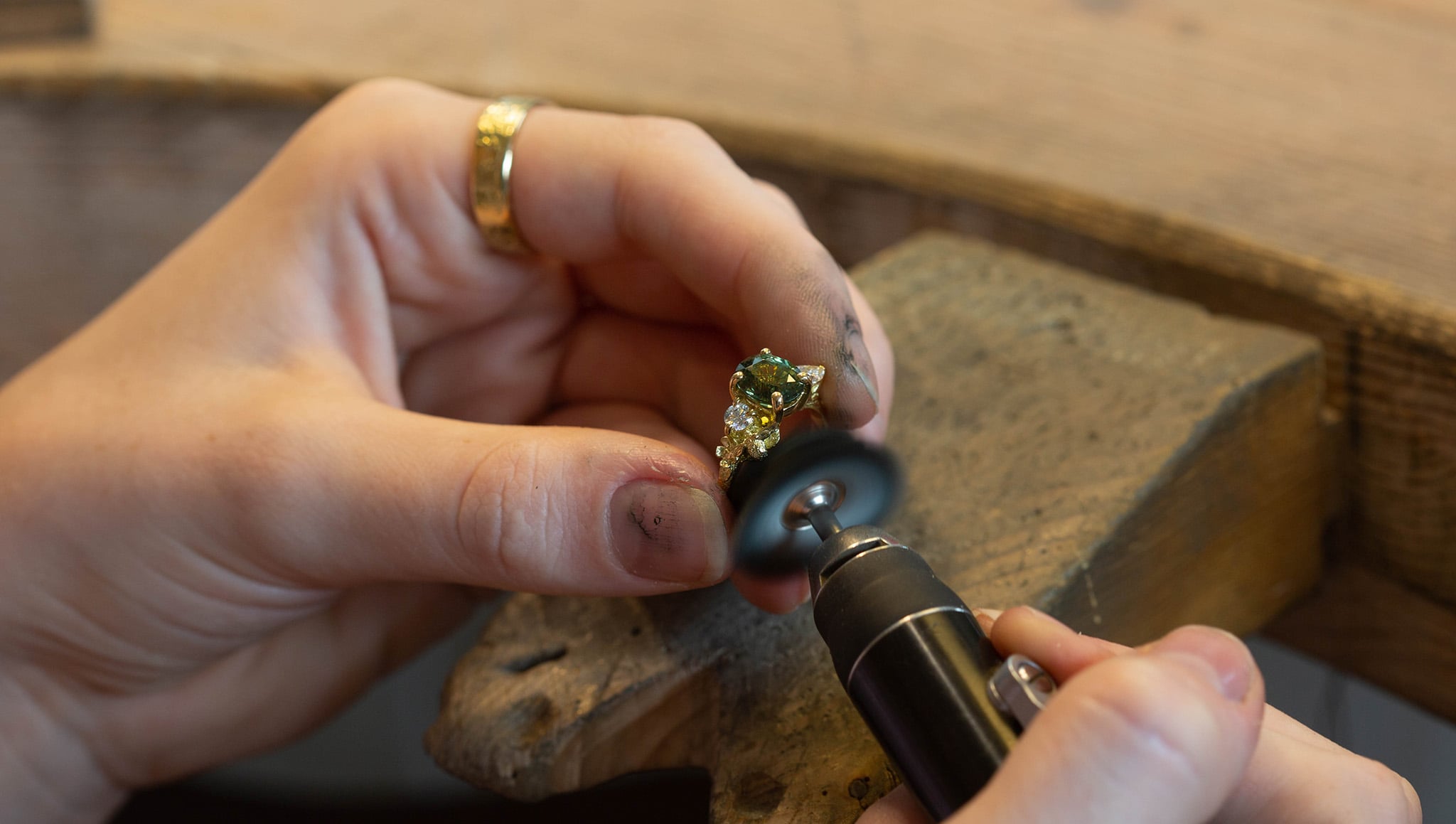 polishing an 18ct gold green sapphire ring at the jewellery bench