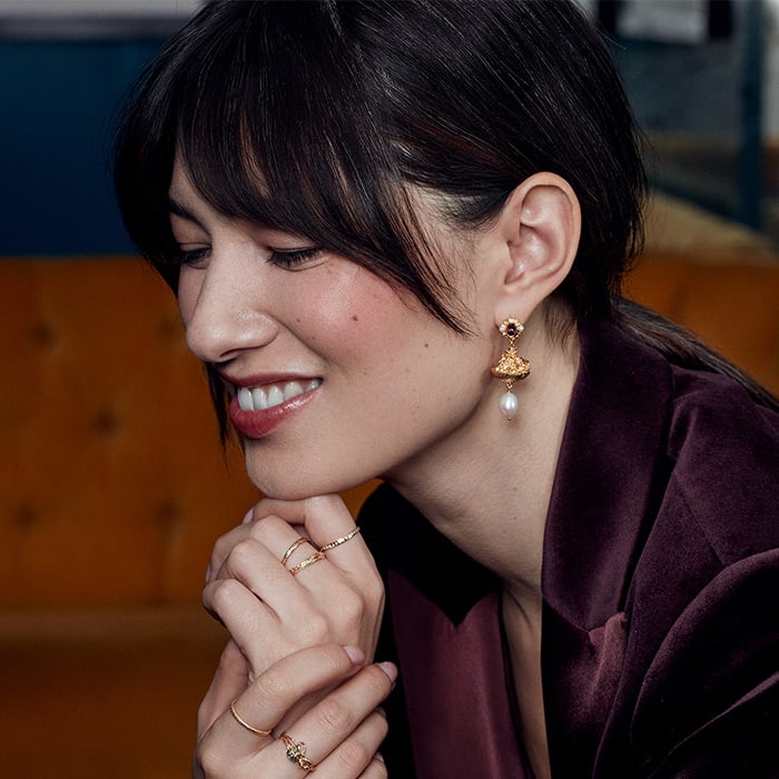 Model wearing Fruit Basket Earrings with Rhodolite Garnet & Freshwater Pearl, she is wearing a purple velvet blazer