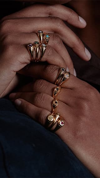 Model wearing 12 birthstone gold plated signet rings by Alex Monroe Jewellery