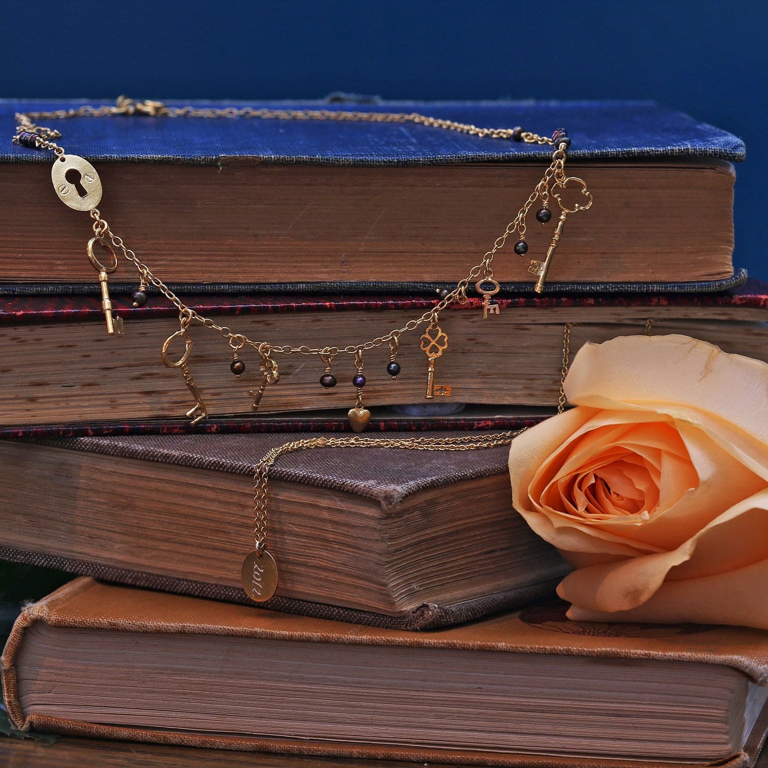 Lock and Key Necklace gold plated silver with black seed pearls displayed on vintage books with peach coloured flower