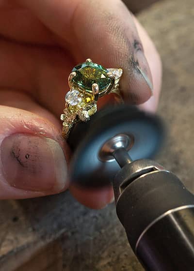 Large blue and green one of a kind bespoke ring being polished at the jewellers bench.