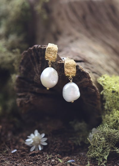 Gold plated Huggie Pearls hanging from a branch