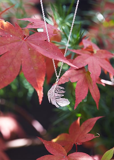 A big gold plated necklace hanging from red leafs