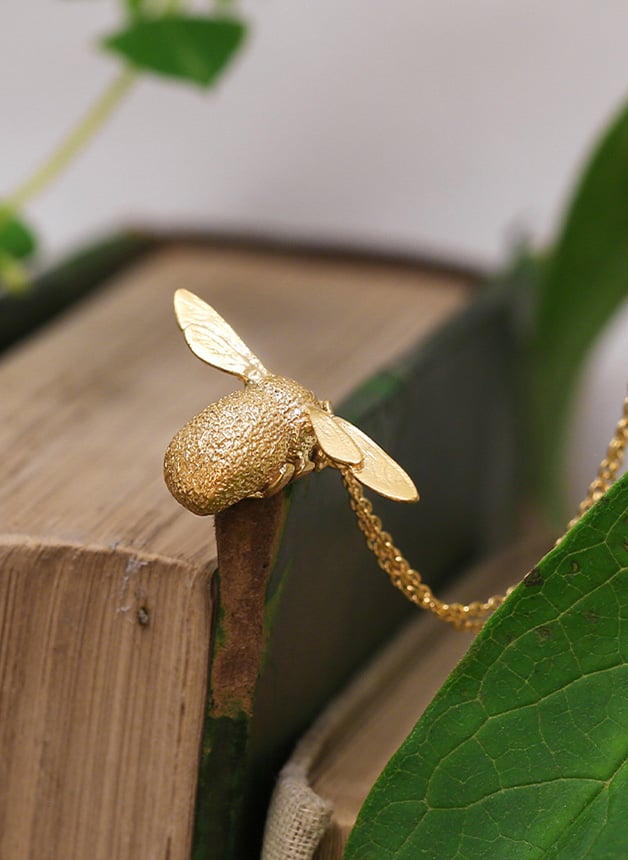 Gold plated Bumblebee Necklace placed on a vintage Book
