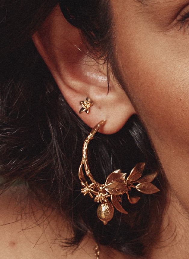 Model wearing gold plated Lemon Blossom Branch Hoop Earrings with Hanging Lemons by Alex Monroe Jewellery