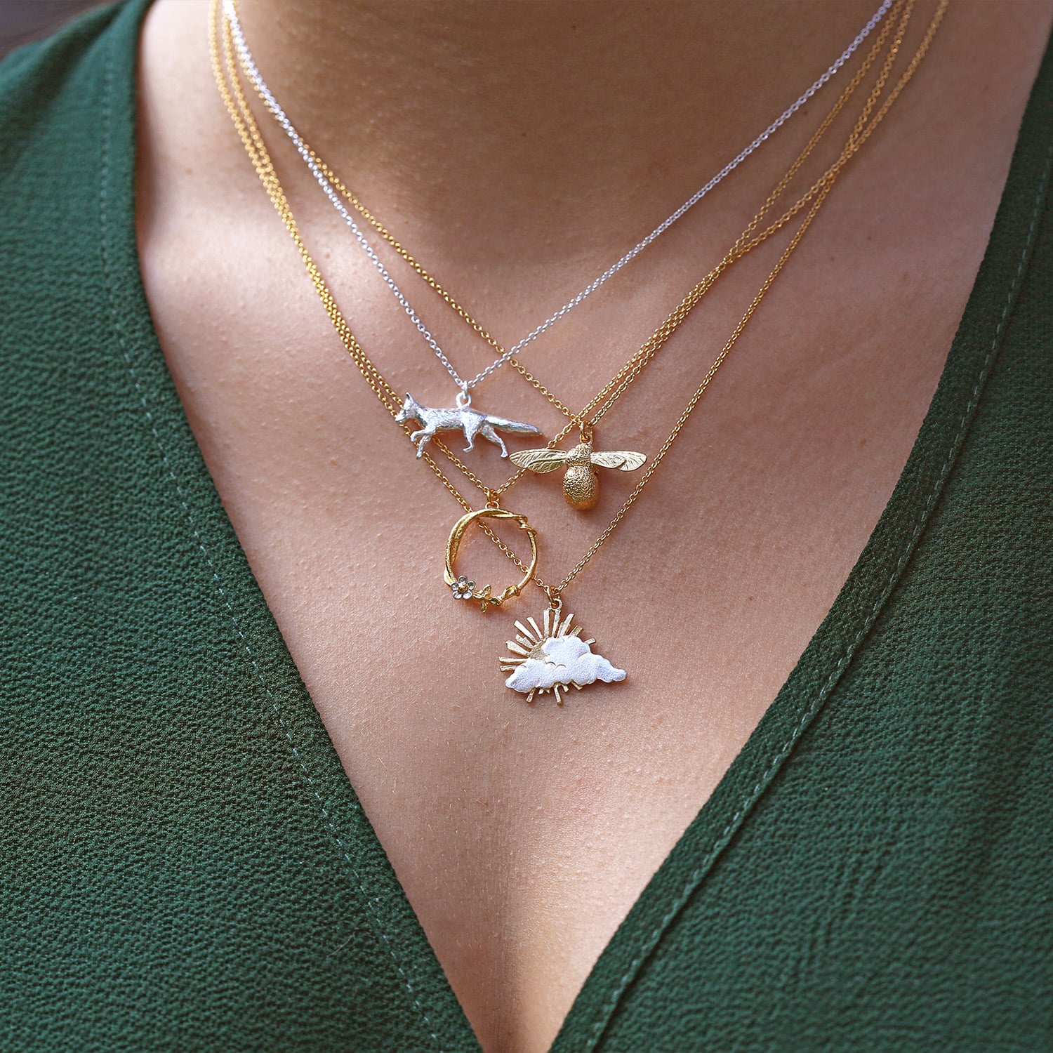 Model wearing baby bee , fox , ray of hope necklaces layered together by Alex Monroe fine jewellery