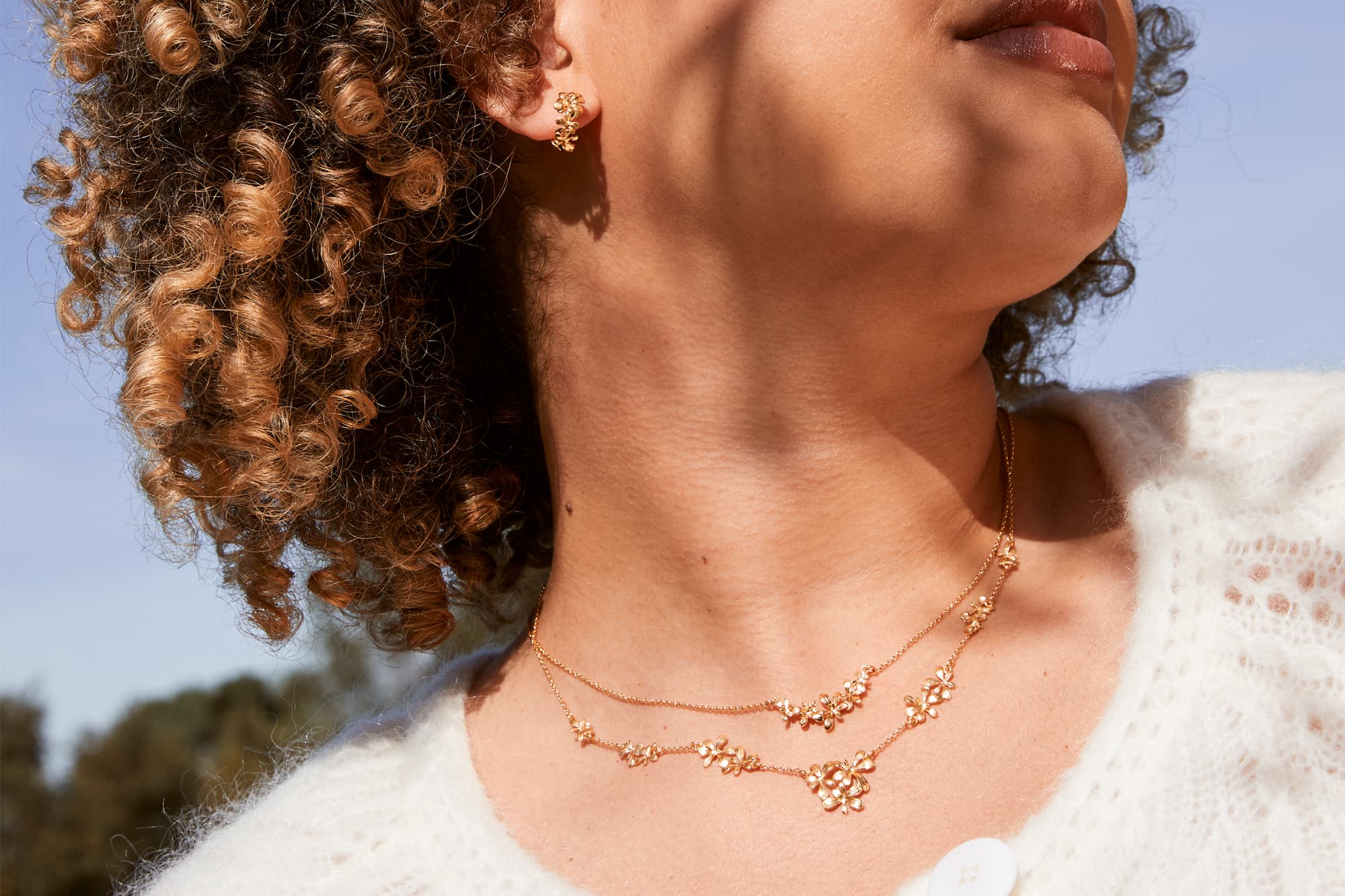 Model wears Rosette Cluster In-Line Pathway Necklace, Sprouting In-Line Necklace and sprouting Rosette Huggie Hoop earrings in sterling silver with fairmined gold plate