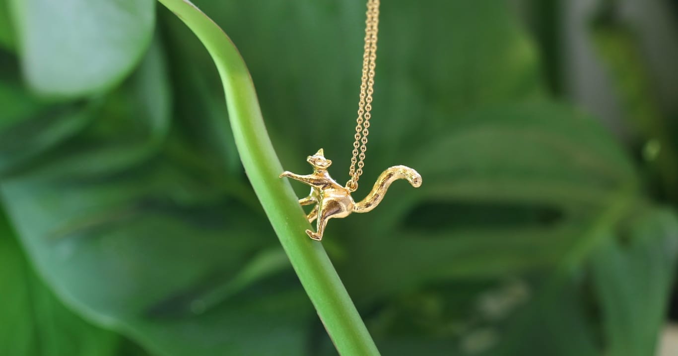 Gold plated Lemur necklace climbing a green plant.