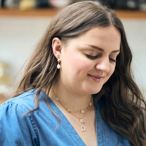 Amy, wearing her Alex Monroe floral letter D necklace, Floral Chain Necklace with Teeny Tiny Bee, Bark Huggie Hoops with Baroque Pearls.
