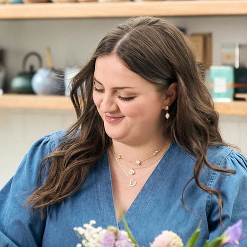 Amy, wearing her Alex Monroe floral letter D necklace, Floral Chain Necklace with Teeny Tiny Bee, Bark Huggie Hoops with Baroque Pearls