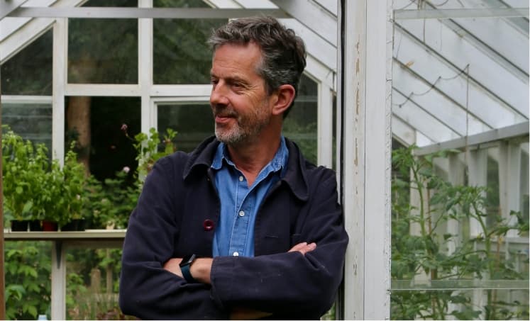 Alex leaning against a pillar in his greenhouse in Suffolk.