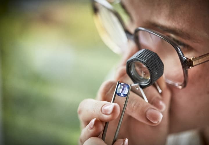 Studying a blue Sri Lankan sapphire with a jeweller's loupe.