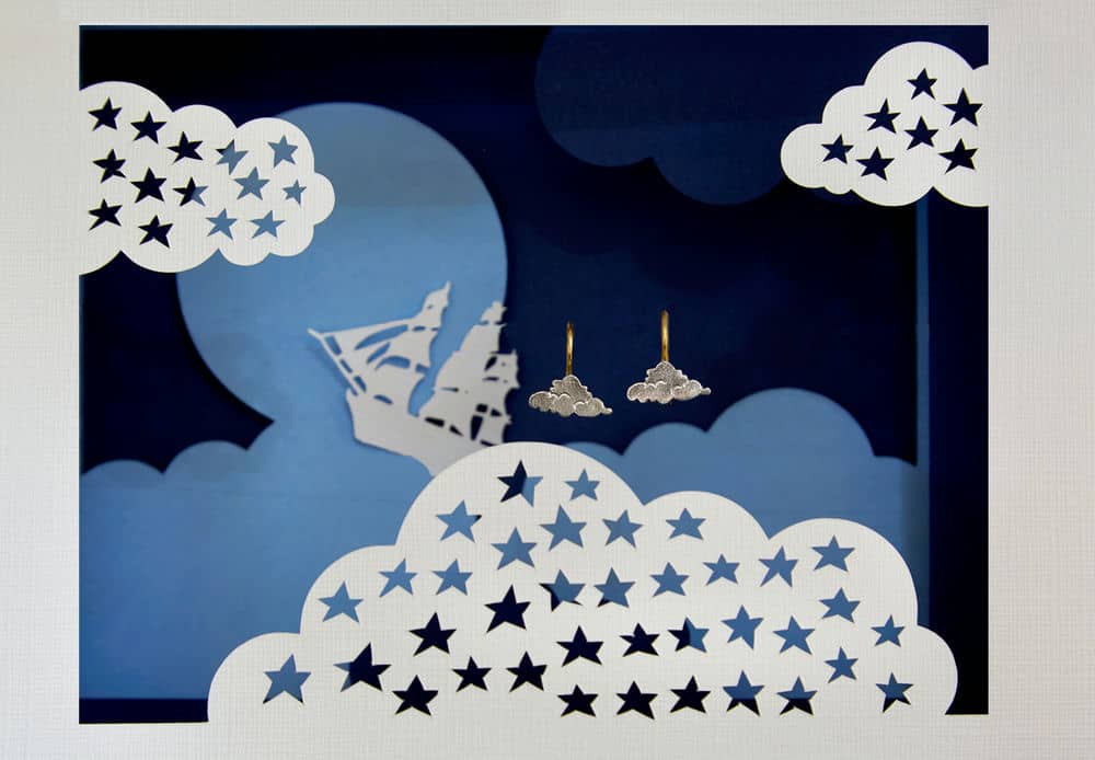 Cloud hook earrings displayed in a paper craft cut-out scene depicting the pirate ship from Peter Pan flying amongst the clouds.