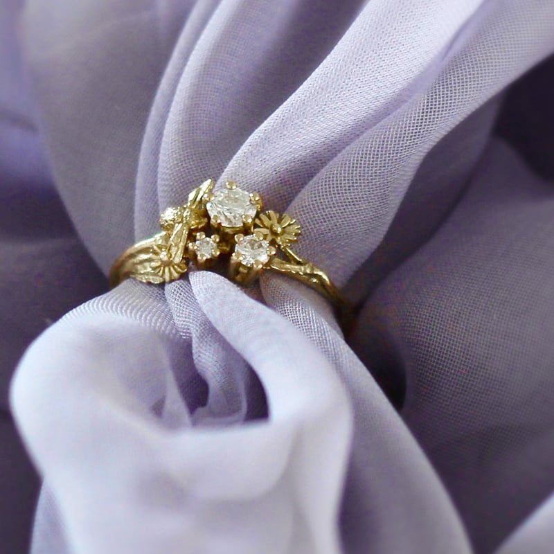 Purple chiffon fabric wrapped around a Beekeeper Three Diamond Trilogy Ring by Alex Monroe Jewellery
