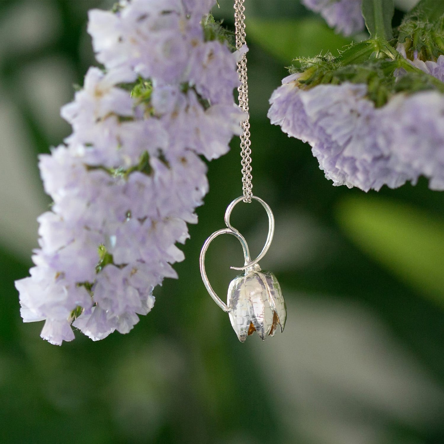 Sterling silver fritillary flower necklace hanging off a branch by Alex Monroe Jewellery