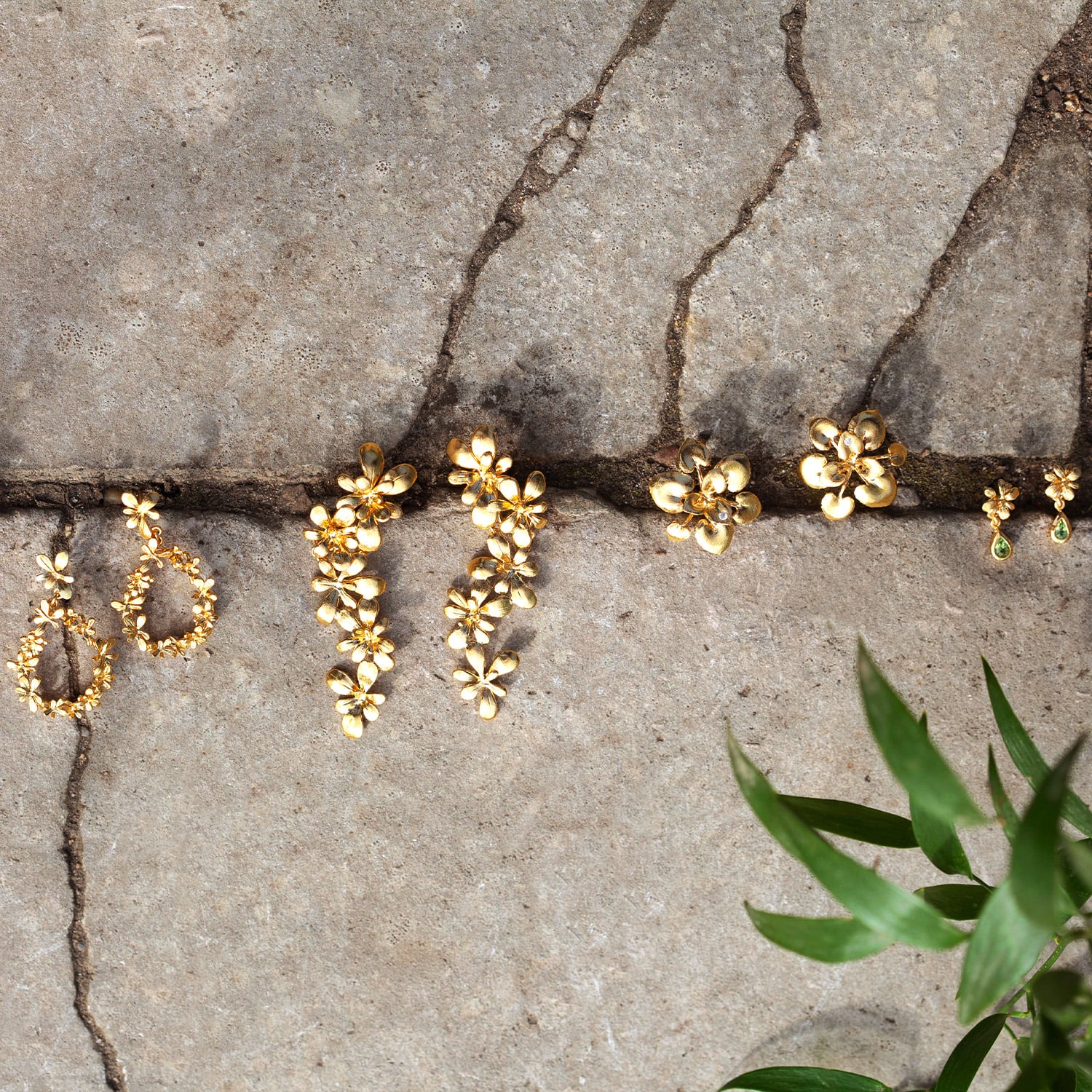 Humble Beginnings gold plated earrings photographed on cracks in concrete pavements by Alex Monroe Jewellery