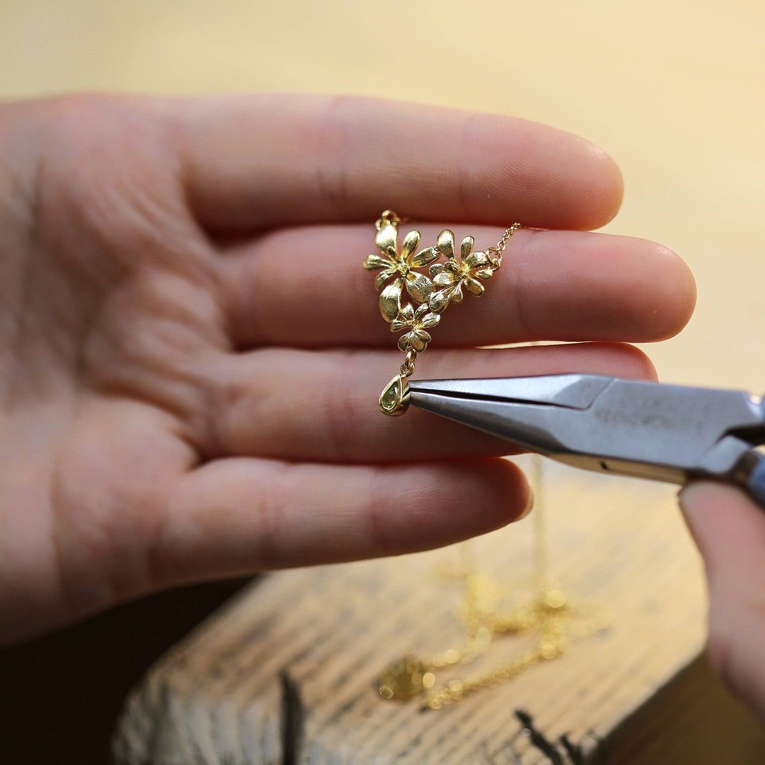 Gold Plated Leafy Rosette Necklace with Green Peridot Teardrop Charm necklace being worked on in Alex Monroe's workshop
